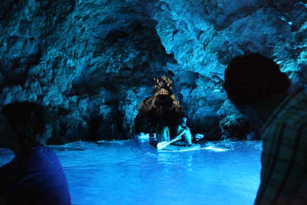 View inside the Blue Cave near Vîs Island showing a small boat with tourists inside the cave.